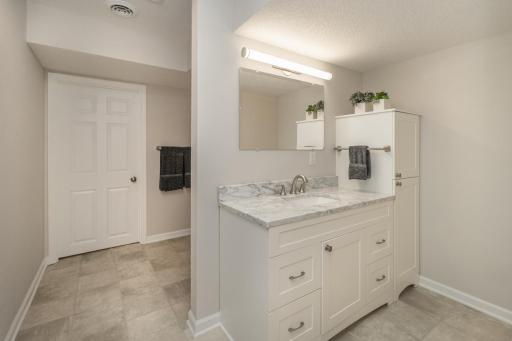 Lower-level 3/4 bath. Shower and stool backside of vanity. Mechanical room through door on back wall.