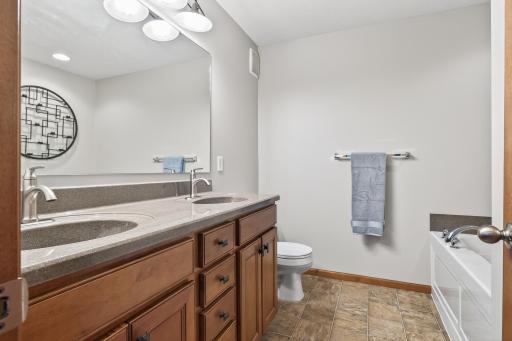 The primary en-suite bathroom features duals sinks on a maple vanity, a deep soaking bathtub, and a walk-in shower.