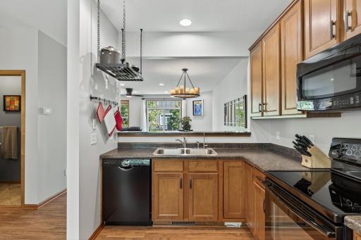 Notice the gorgeous upgraded maple cabinets, wood flooring, a convenient and durable hanging rack for pots and pans, and a space saving built-in microwave.