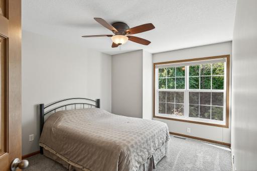 The second bedroom on the upper level also includes new carpet, fresh paint, and a ceiling fan with a light. This bedroom looks out to the wooded front yard.