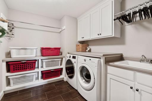 Upper level full laundry with sink and multiple drying and hanging racks and built-in storage