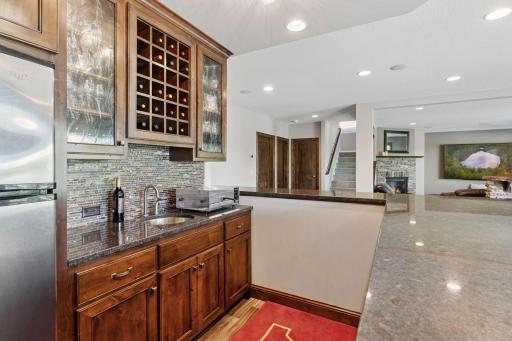Full lower level wet bar, granite counter, tile backsplash, wine racks and glass-faced cabinetry