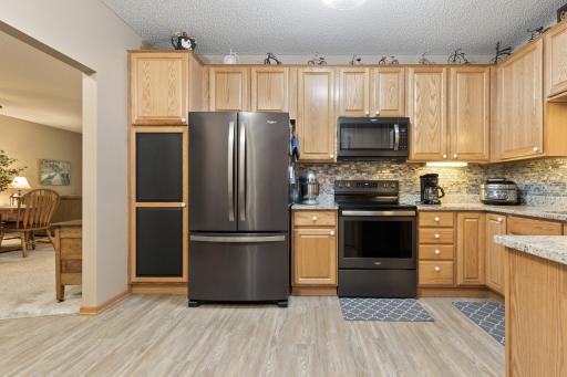 Updated Kitchen with solid surface countertops, black stainless steel appliances, tiled backsplash, under cabinet lights, and laminate floors