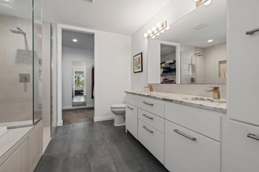 Spa-like primary bathroom with tile floors, dual vanity, separate tub & walk-in shower