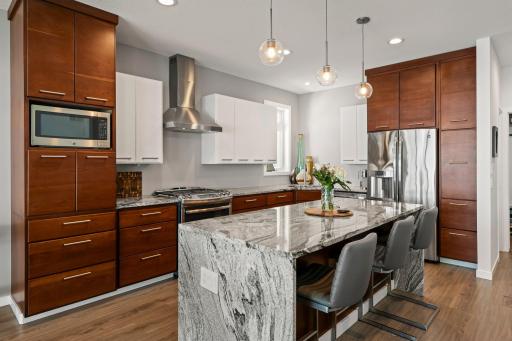 Gorgeous kitchen features granite counters with waterfall edge, stainless appliances, gas range & breakfast seating at the island