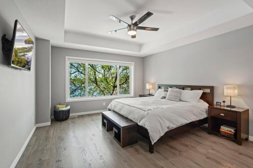 Primary bedroom is a quiet retreat offering lake views & sleek hardwood floors