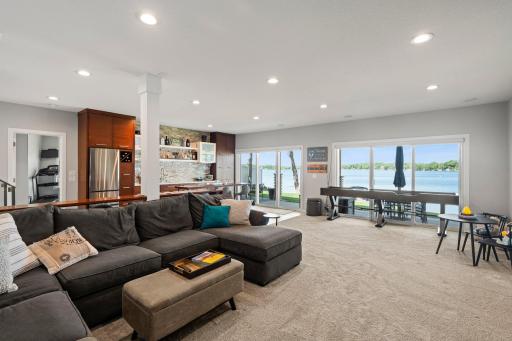 The expansive lower level is perfect for entertaining, featuring a generous family room, rec space, custom wet bar, and a wall of windows showcasing stunning lake views