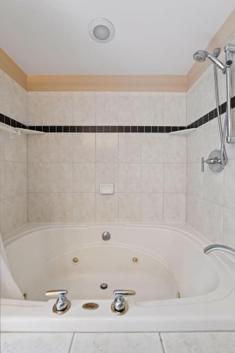Spacious full tub with tile surround, offering both comfort and timeless style.
