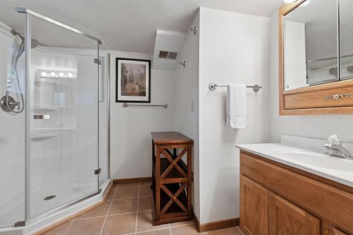 Lower-level Â¾ bath featuring tasteful tile finishes, a glass-enclosed shower, modern vanity, and stoolâdesigned for both style and functionality.