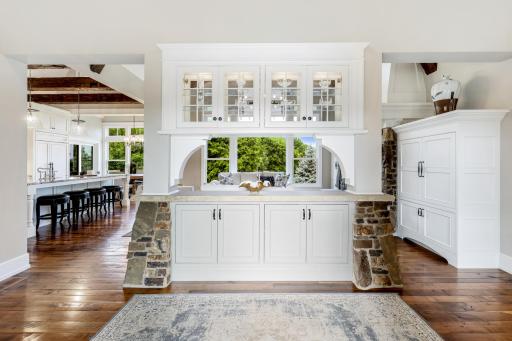 Custom built-in with enameled cabinetry (lighted glass display uppers), stacked stone accents and stone counter