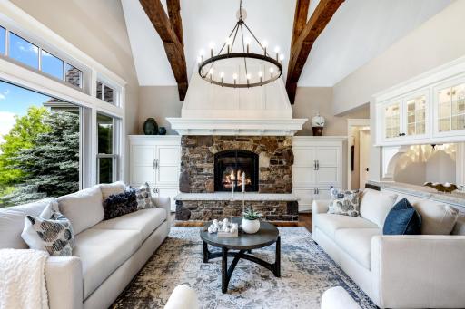 Gas fireplace with stacked stone surround, stone hearth + enameled mantel & decorative millwork to the ceiling.