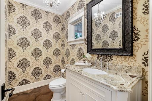 Powder bath with crown molding, designer wallpaper, tile floors, and granite vanity.
