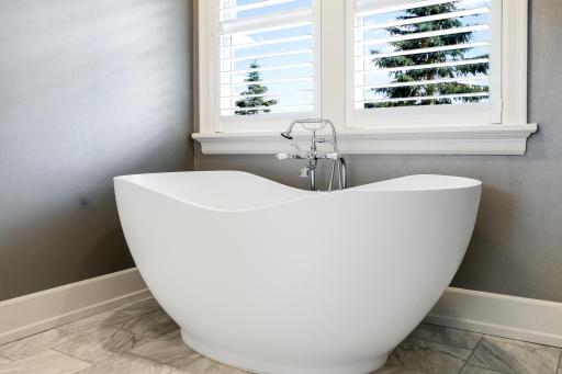Spacious open area includes a freestanding soaking tub and large, walk-in, tile shower.