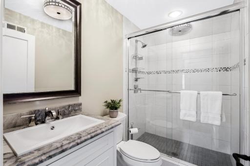 En-suite Â¾ bath with tile floors, enameled vanity & shower with tile surround & glass door.