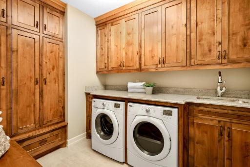 A second laundry room equipped with built-in storage, tile floors, sink and folding counter. Yes granite countertops!