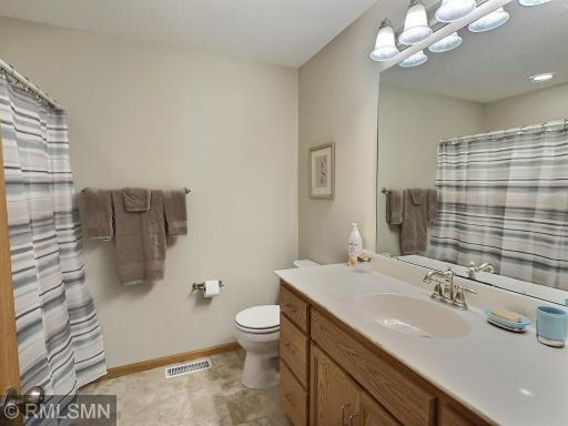 This full bathroom offers a clean and functional layout with a large vanity, ample storage, and an expansive mirror with overhead lighting.