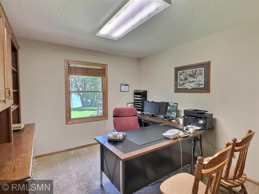 Lakeside views and natural sunlight fill the second main level bedroom, currently being used as an office with plush carpeting and natural tones.