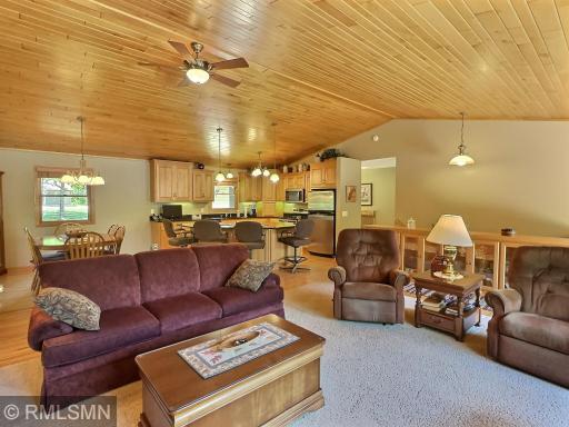 This inviting and vaulted living room features an open-concept layout that flows seamlessly into the kitchen and dining areas.