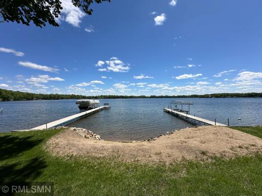 The meticulously maintained yard opens to 93 feet of sandy shoreline, perfect for swimming, relaxing, and taking in peaceful views.