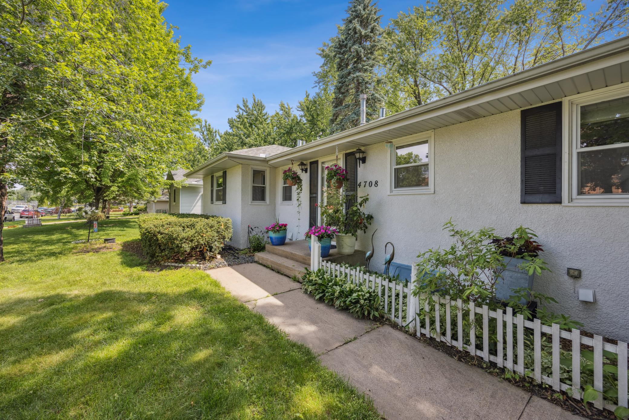 Angled view of front of home, sidewalk and landscaping. Leaf gutter guards on home.
