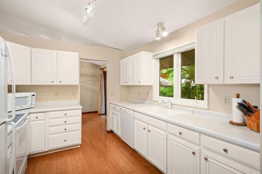 Bright, modern white kitchen featuring generous storage and counter space, with a view of the backyard.