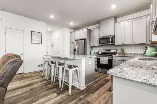 Fully stocked kitchen with stainless steel appliances including gas range, microwave with true exhaust system, and dishwasher. Kitchen island doubles as not only additional storage space, but a breakfast bar.