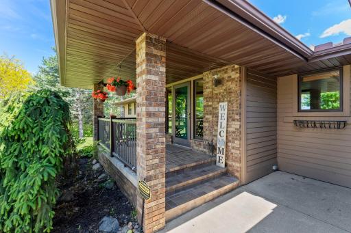 Covered front porch with cobblestone pavers and brick accents.