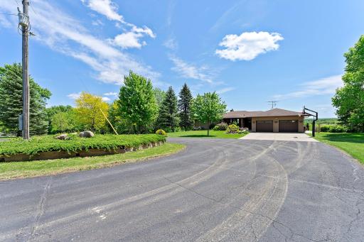Massive sweeping turnaround driveway provides access to both the home and partially finished pole barn.