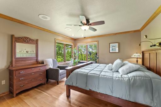 Primary Bedroom with Hardwood Floors, Corner Windows, Crown Molding, Ceiling Fan and Large Walk-in Closet.