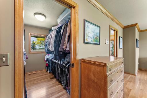 Primary bedroom walk-in closet with hardwood flooring and pocket door.