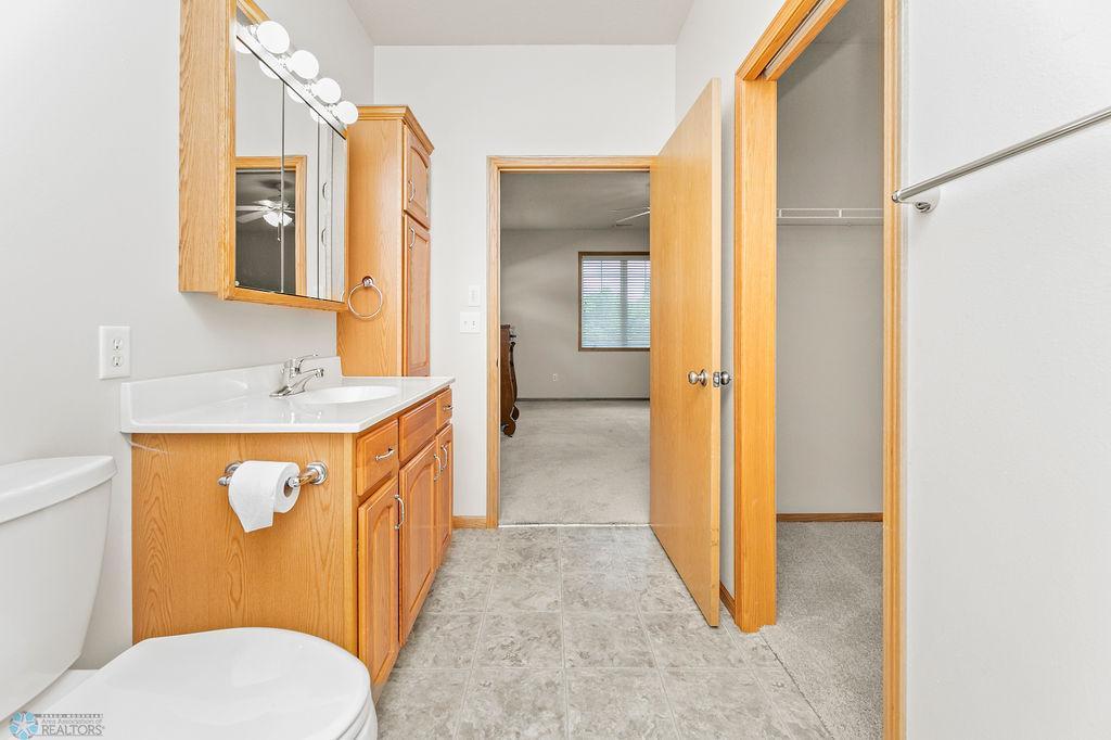 Spacious bathroom with linen cabinet, connects to large WIC