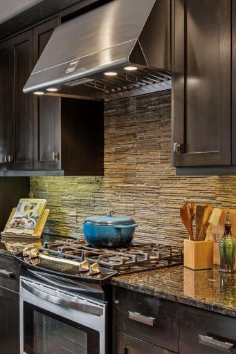 Beautiful stone backsplash really heighten the luxurious kitchen.