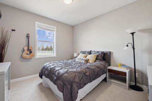 The main-level office offers flexibility and comfort, currently serving as a cozy guest room. Soft carpeting underfoot and a large window overlooking the expansive backyard create a warm, welcoming atmosphere.