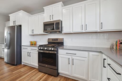 Bright white staggered cabinets, a stunning backsplash and stainless-steel appliances enhance the kitchenâs elegant appeal.