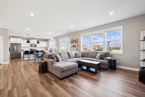 Abundant natural light pours through large windows, highlighting the flooring and bright white cabinetry. Modern pendant lighting and sleek finishes add a touch of sophistication to this beautifully designed interior.