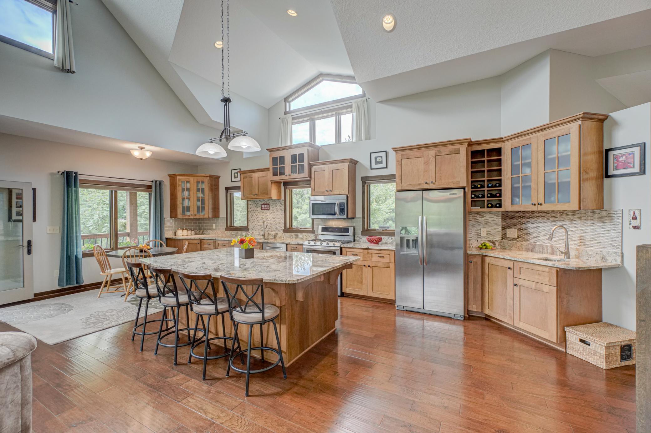 Step inside to a sunlit open layout with soaring ceilings, hickory wood floors, Marvin Integrity windows w/custom blinds, Maple cabinetry w/under-cabinet lighting, & a stylish wine cabinet. Direct access to the screened porch and wraparound deck.