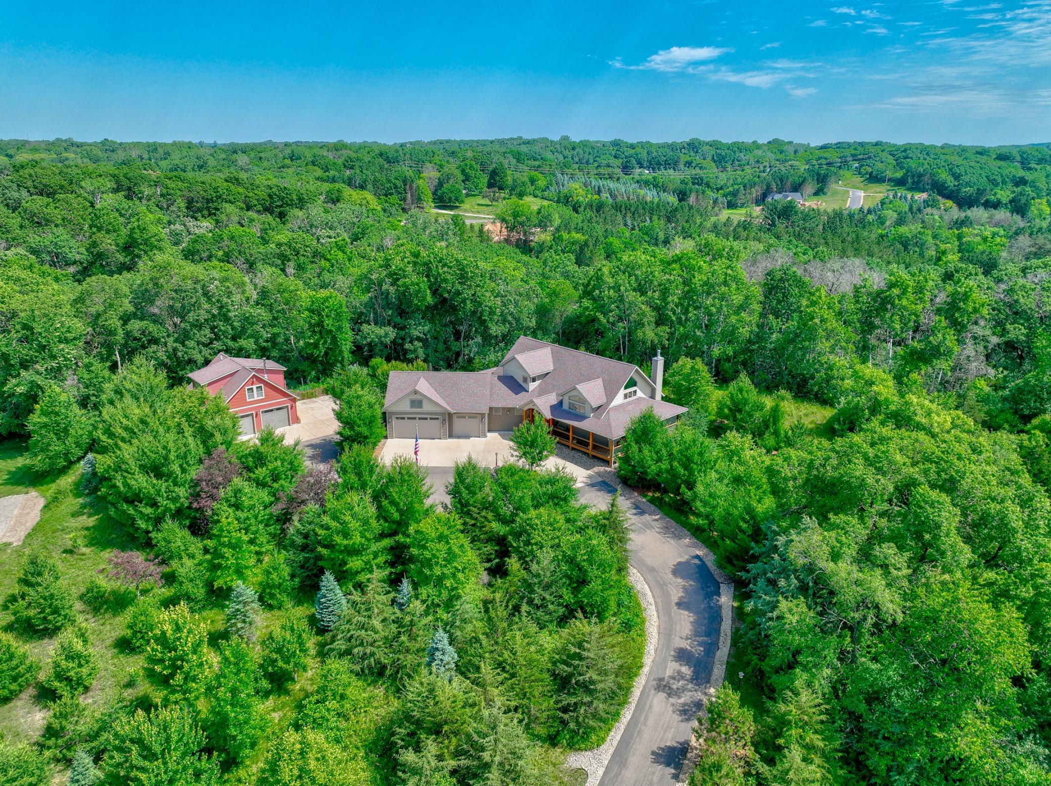An oversized circle drive, 3-car attached garage, and a 2-car heated and cooled detached garage/workshop with an additional living area above—including a kitchenette, bathroom, and wood-burning stove.