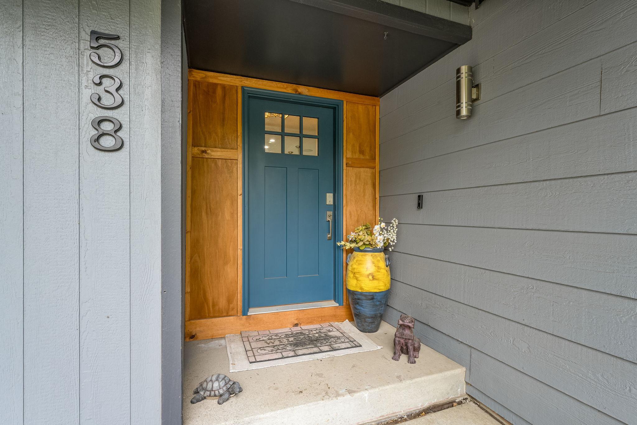 Inviting front entry with a bold blue door, natural wood trim accents, and a cozy covered porch.