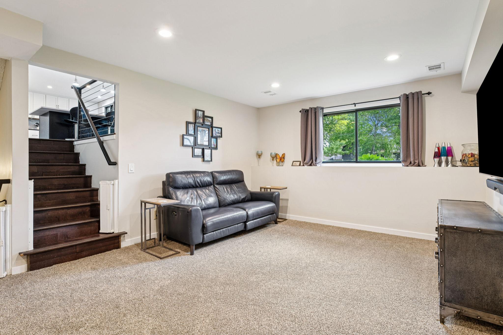 Comfortable and inviting lower-level family room featuring carpet, recessed lighting, and large window with backyard views.