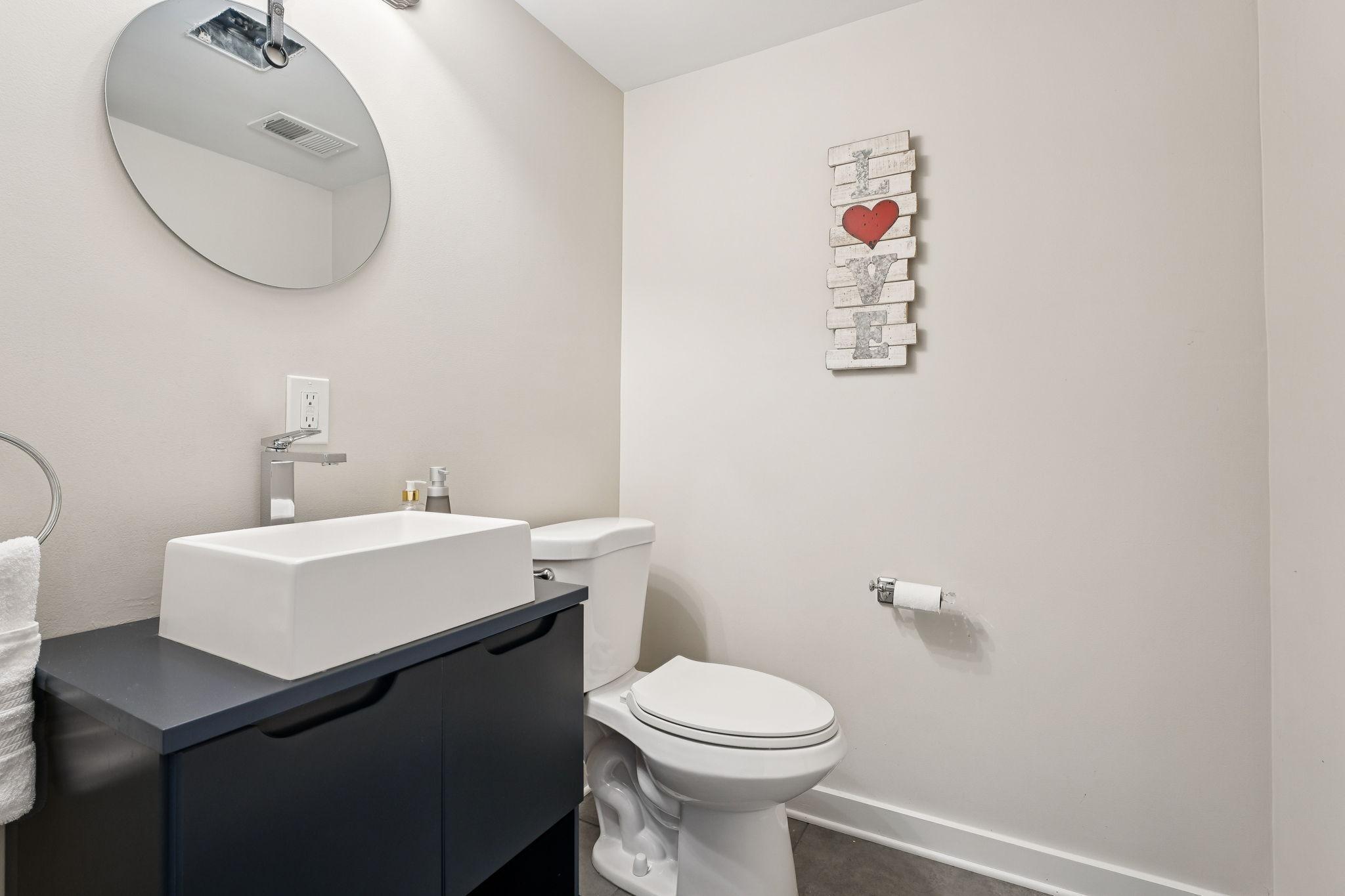 Sleek and modern half bath featuring a stylish rectangular vessel sink, contemporary faucet, and floating vanity with storage.