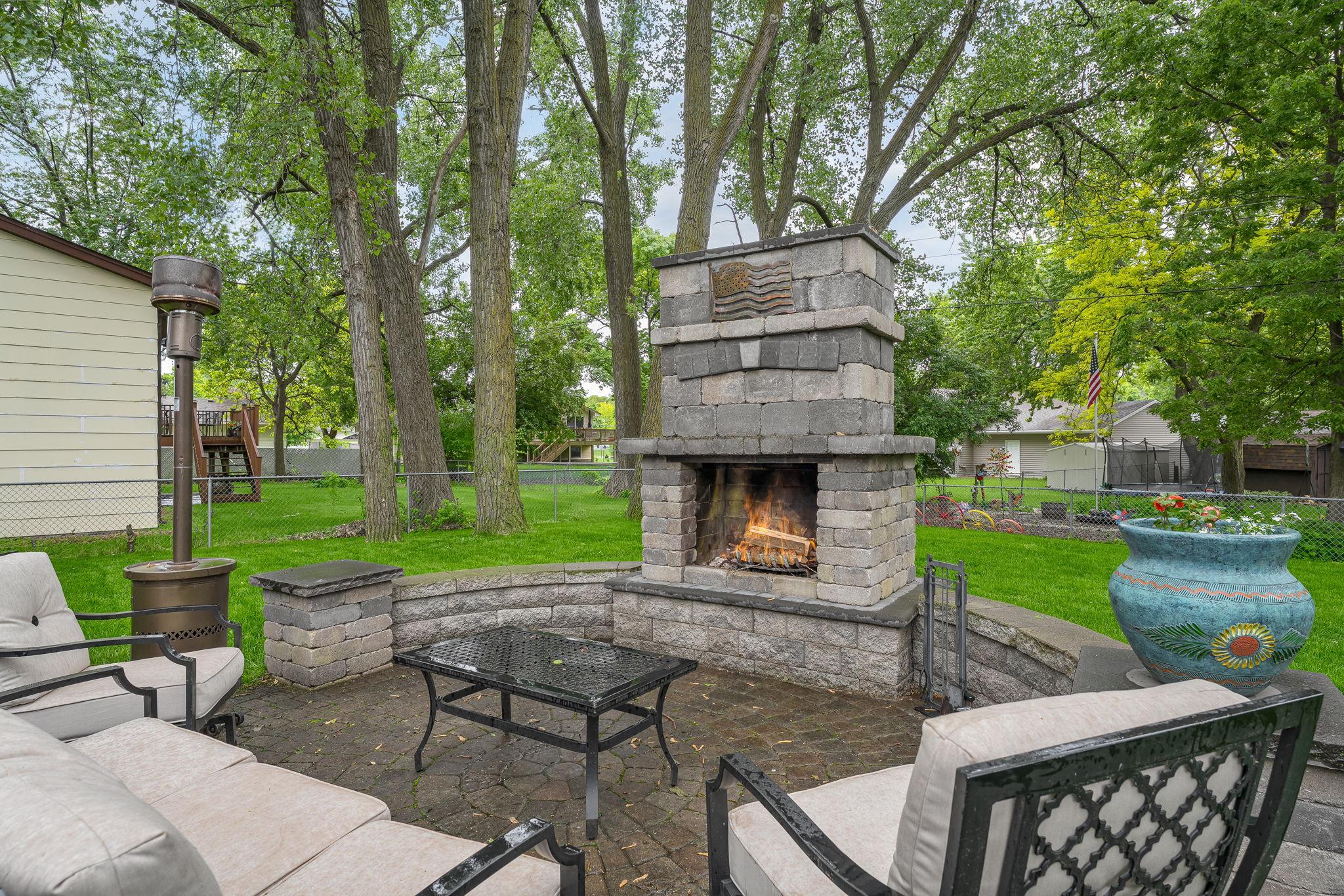 Relax in the dedicated outdoor lounge space featuring a large stone fireplace, ample seating, and beautiful landscaping. A peaceful and private retreat.