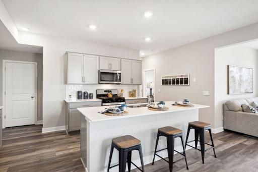 A spacious kitchen island for the family to gather around during informal meals. This home does have grey cabinets throughout. *Picture is of previously completed and staged model...
