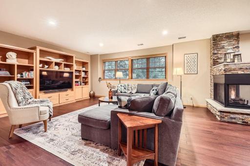 The inviting lower-level family room is designed for both relaxation and entertaining, featuring a cozy fireplace, custom built-ins, and generous space for gatherings, game nights, or quiet evenings in.