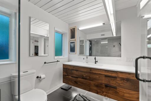 The gorgeous wood and under lighting of the primary suite's vanity are representative of the sophistication and care that went into the bathroom renovations throughout the home.
