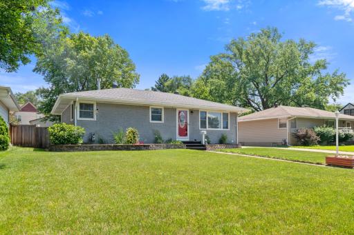 Another angle showcasing the wide concrete driveway and updated front steps, framed by a well-maintained lawn.