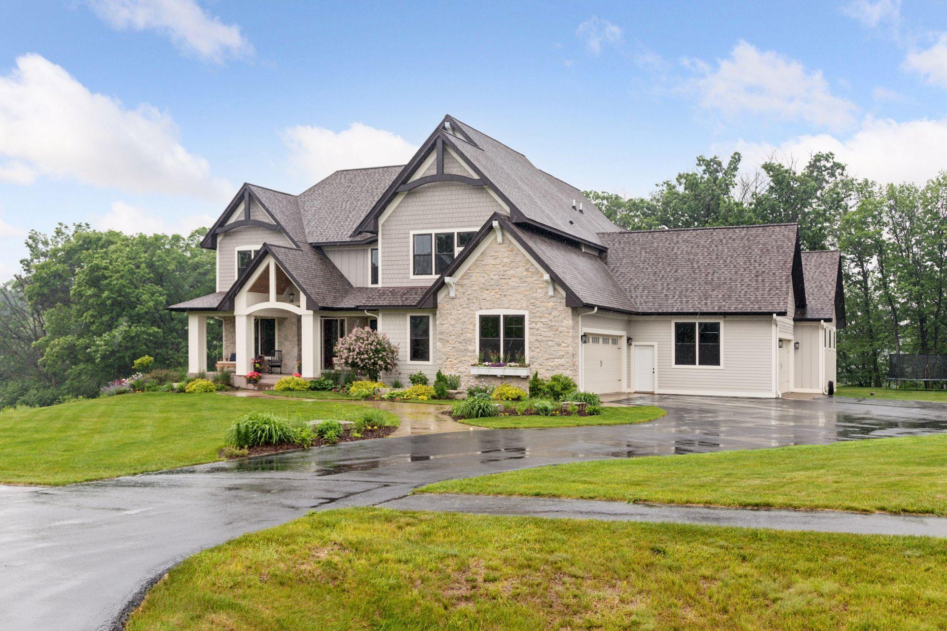 This front view shows the the home's curb appeal: beautiful exterior finishes, a large driveway for parking or activates and its beautiful landscaping.