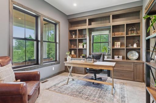 Private main-level office with custom built-ins, large windows, and natural wood trim â perfect for working from home.