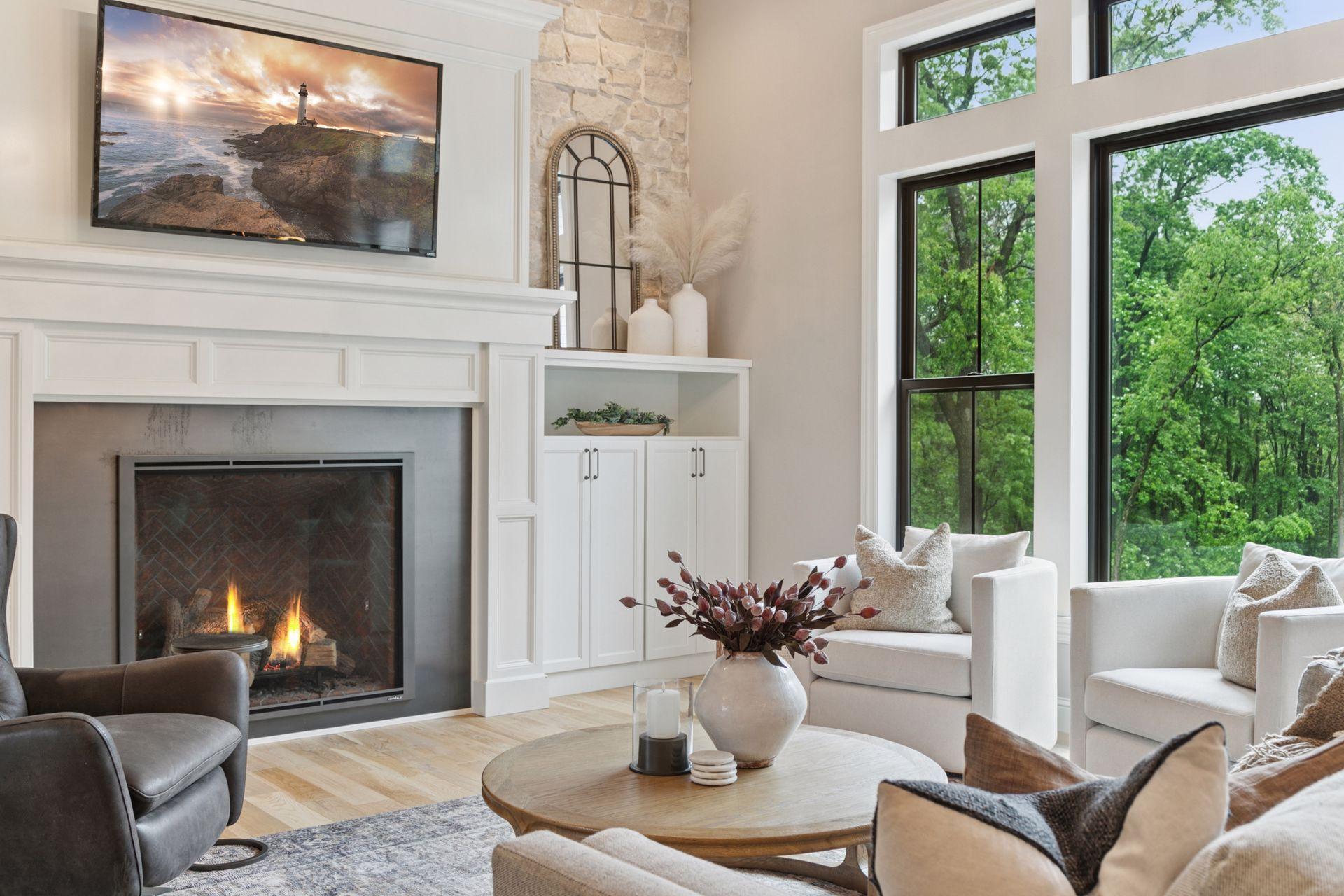 Spacious seating area with cozy textures, fireplace ambiance, and views of backyard pool and the wooded landscape just beyond the windows.