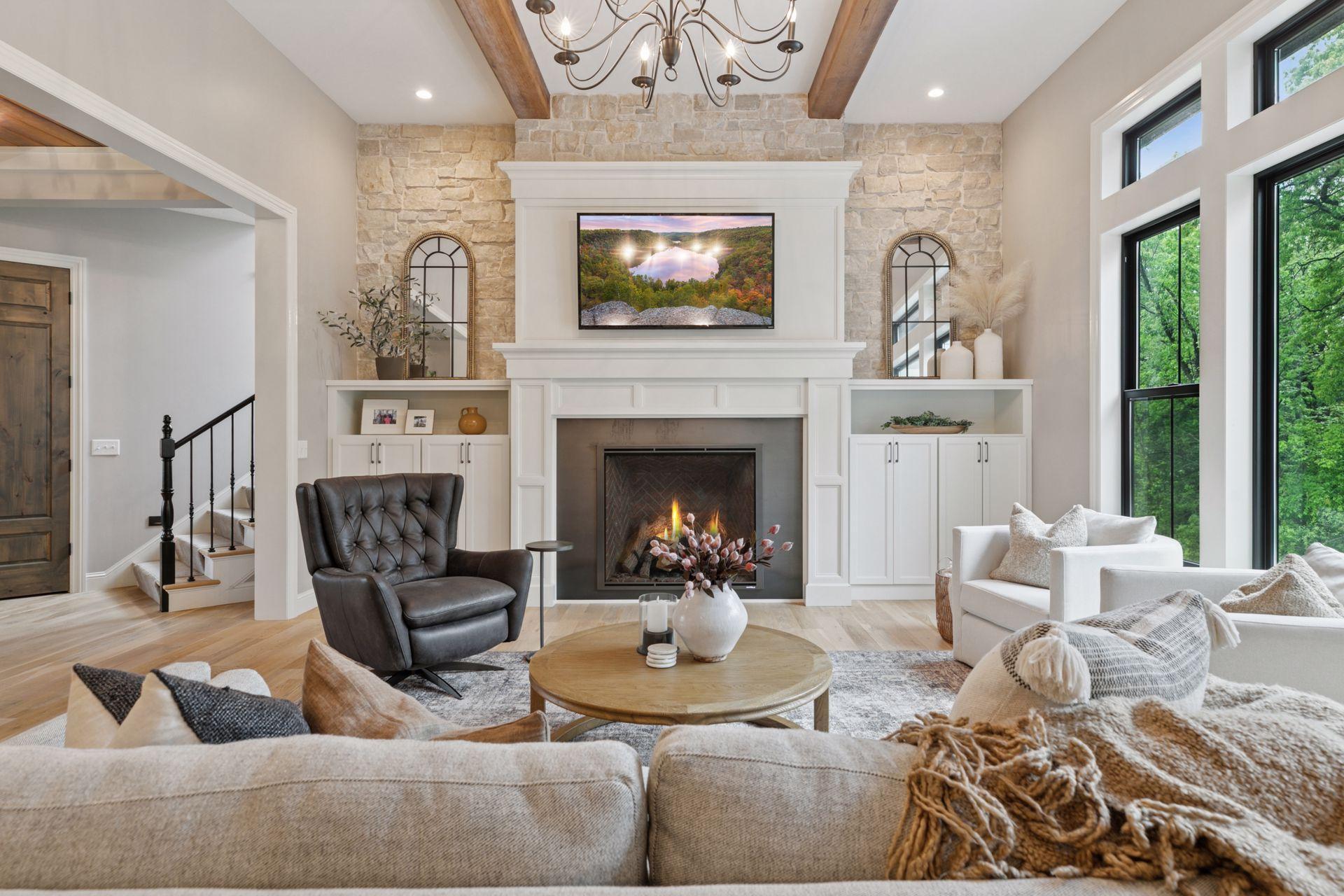 Cozy and elegant living area with a stunning stone fireplace, built-in cabinetry, and abundant natural light from oversized windows.