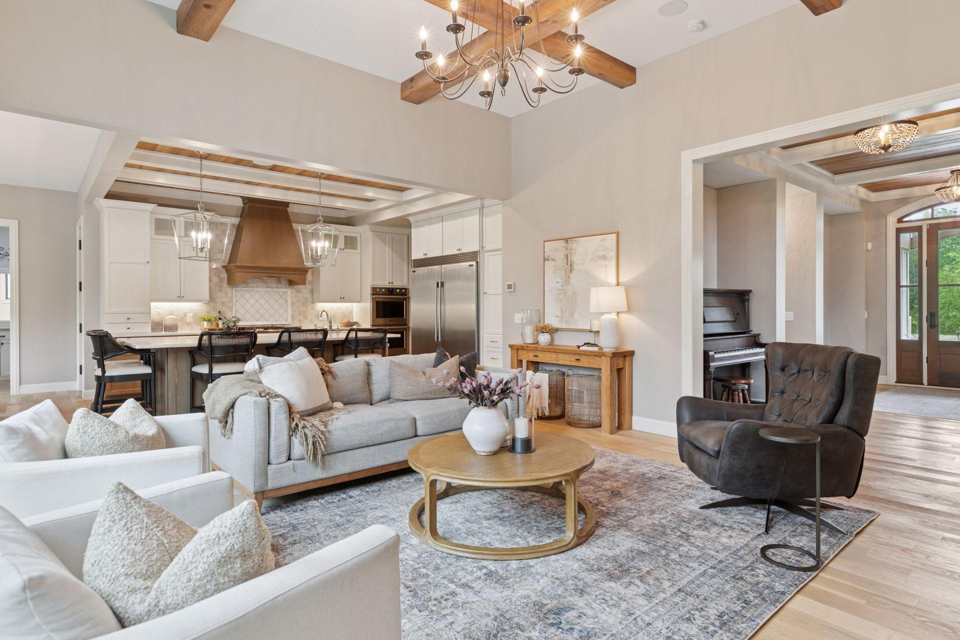 Beautiful open-concept living space with beamed ceilings and seamless flow from the living room to the kitchen and entryway.